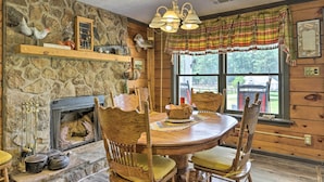 A rustic dining area with a stone fireplace, wooden chairs, and a table. - Buckhead Cabin w/ Fireplaces & Private Pool! (Buckhead)