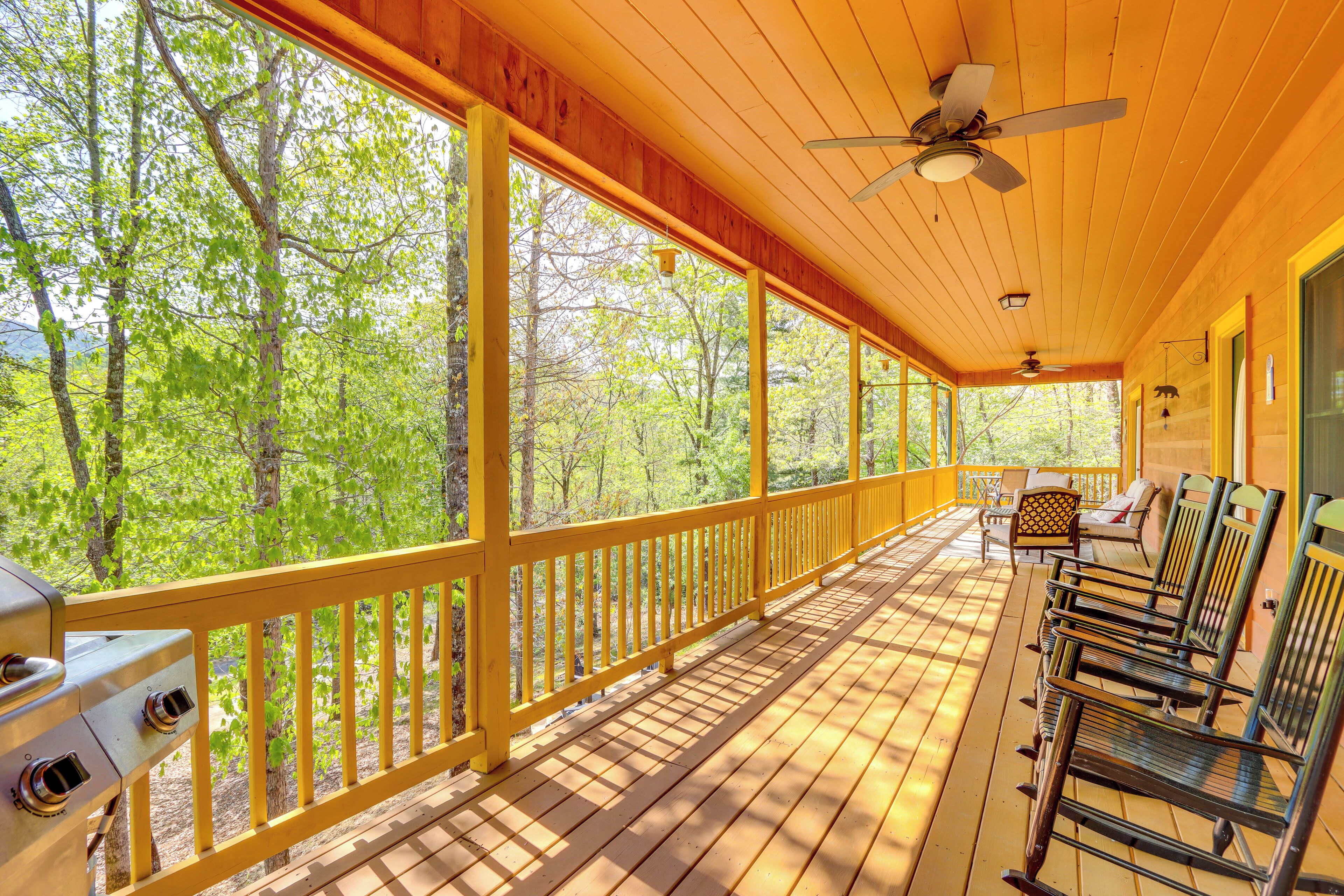 A covered porch with wooden railings, a grill, and outdoor seating.