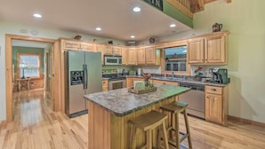 Una cocina amplia con armarios de madera, encimera de granito y una isla central con taburetes de bar.