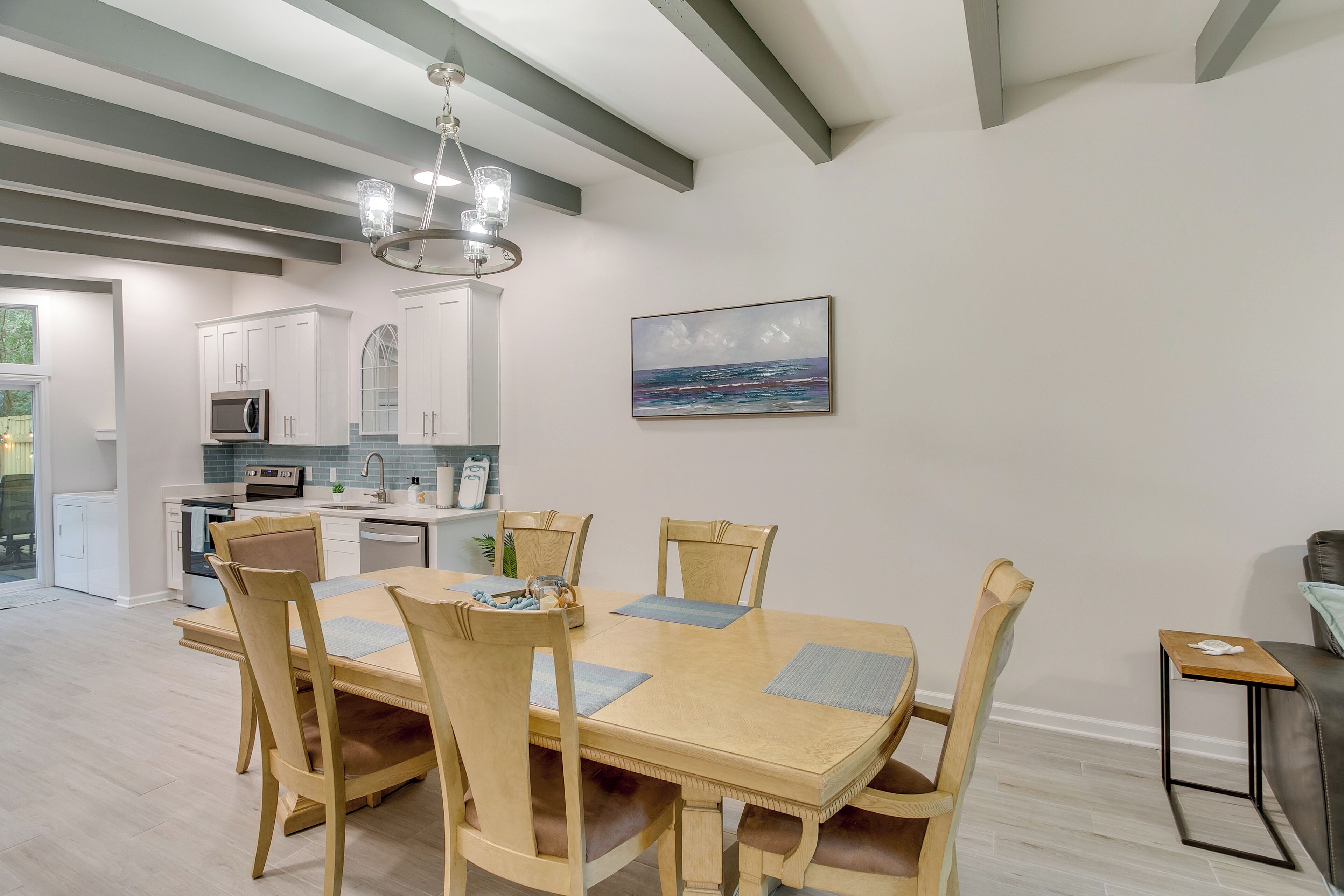 A modern kitchen with white cabinets, a microwave, and a dining area with a wooden table and chairs.