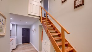 Un escalier en bois menant à l’étage supérieur, une armoire blanche et une porte dans un couloir.