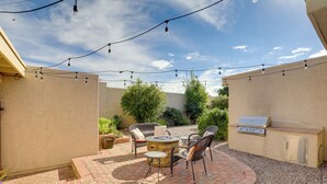 A patio with a round table, chairs, a grill, and string lights. - Sunny Tucson Townhome w/ Patio & Mountain Views! (Tucson)