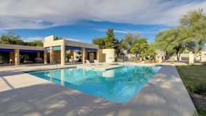 A swimming pool with a clear blue water surface, surrounded by a concrete deck and a building with a flat roof and large windows. - Sunny Tucson Townhome w/ Patio & Mountain Views! (Tucson)