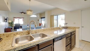 A kitchen with granite countertops, stainless steel sink, and a dishwasher. - Sunny Tucson Townhome w/ Patio & Mountain Views! (Tucson)