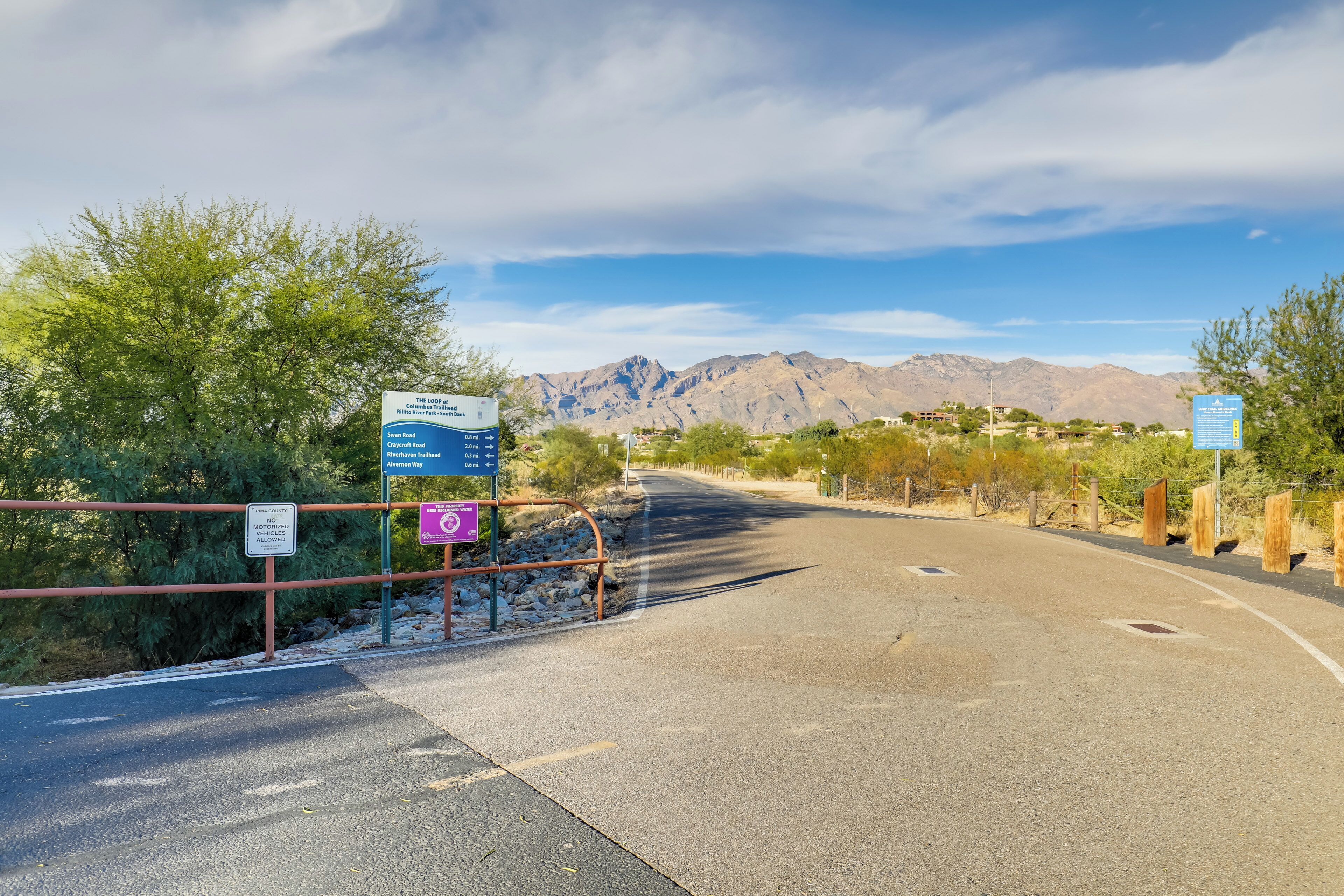 Una carretera que conduce a una cordillera, con señales indicando senderos.
