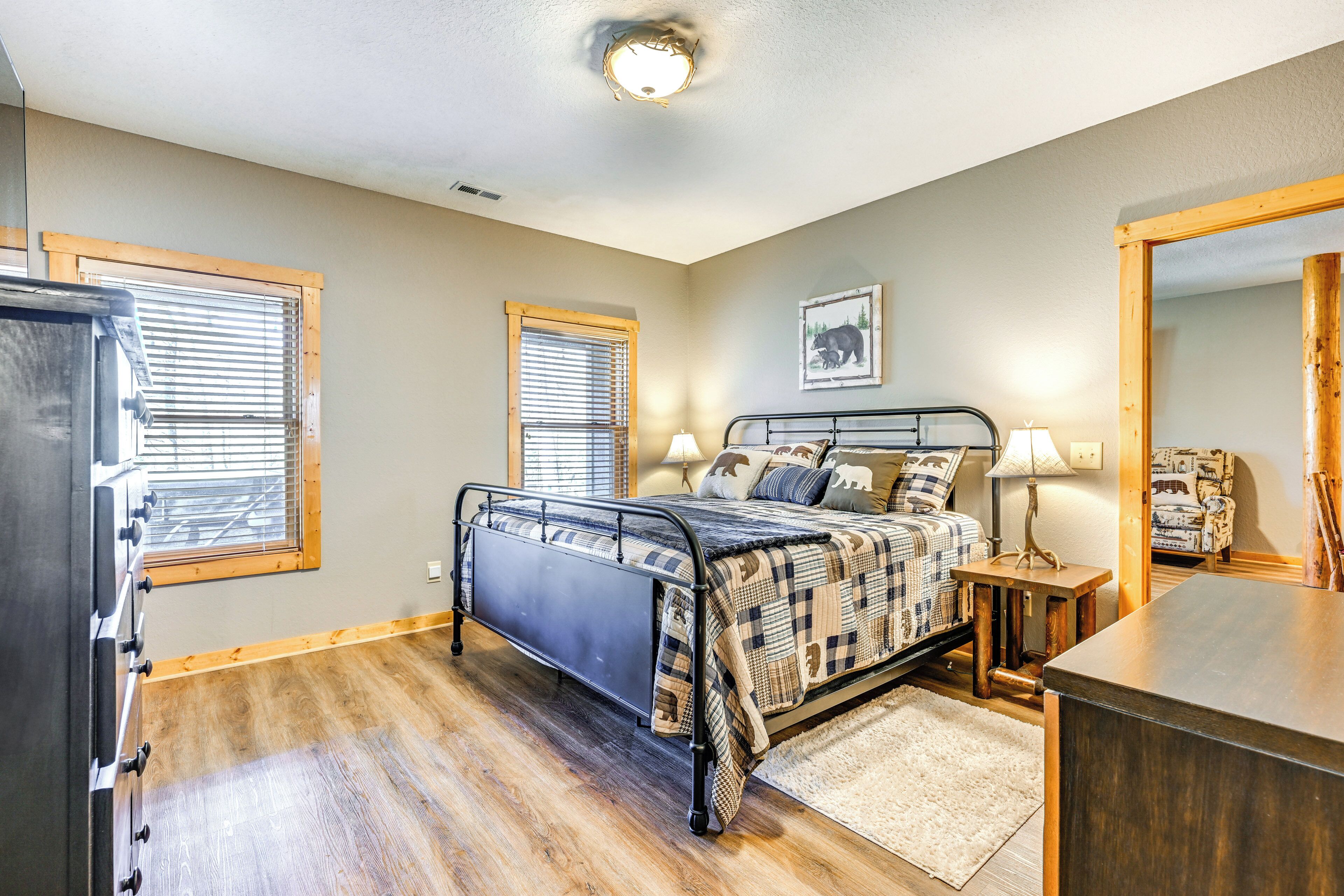 A bedroom with a bed, bedside lamps, a dresser, and a large mirror.