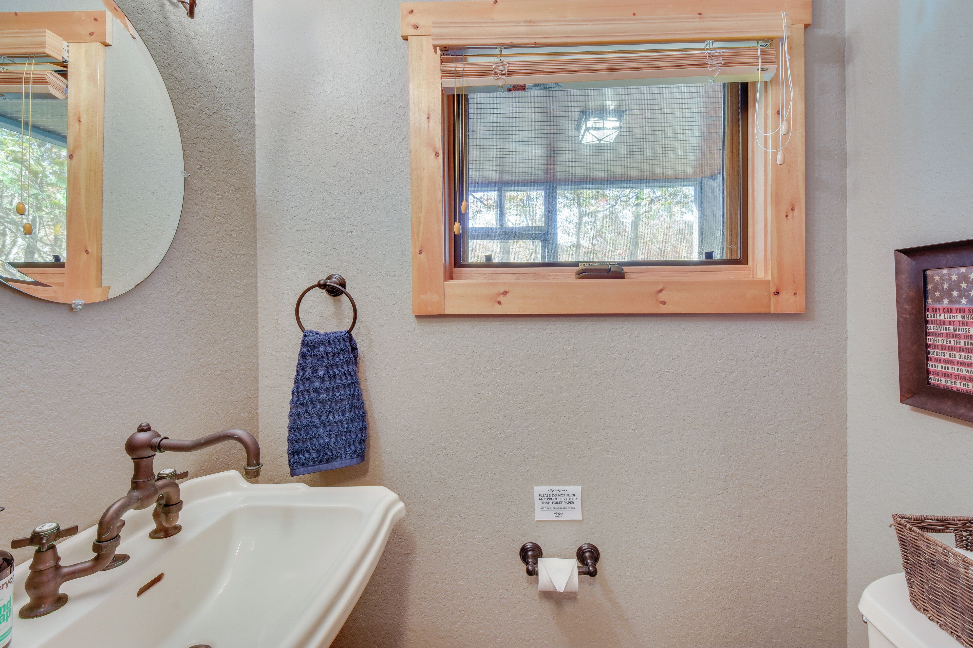 Une salle de bain équipée d’un lavabo, d’un miroir, d’une fenêtre, d’un porte-serviettes et d’un support à papier toilette.