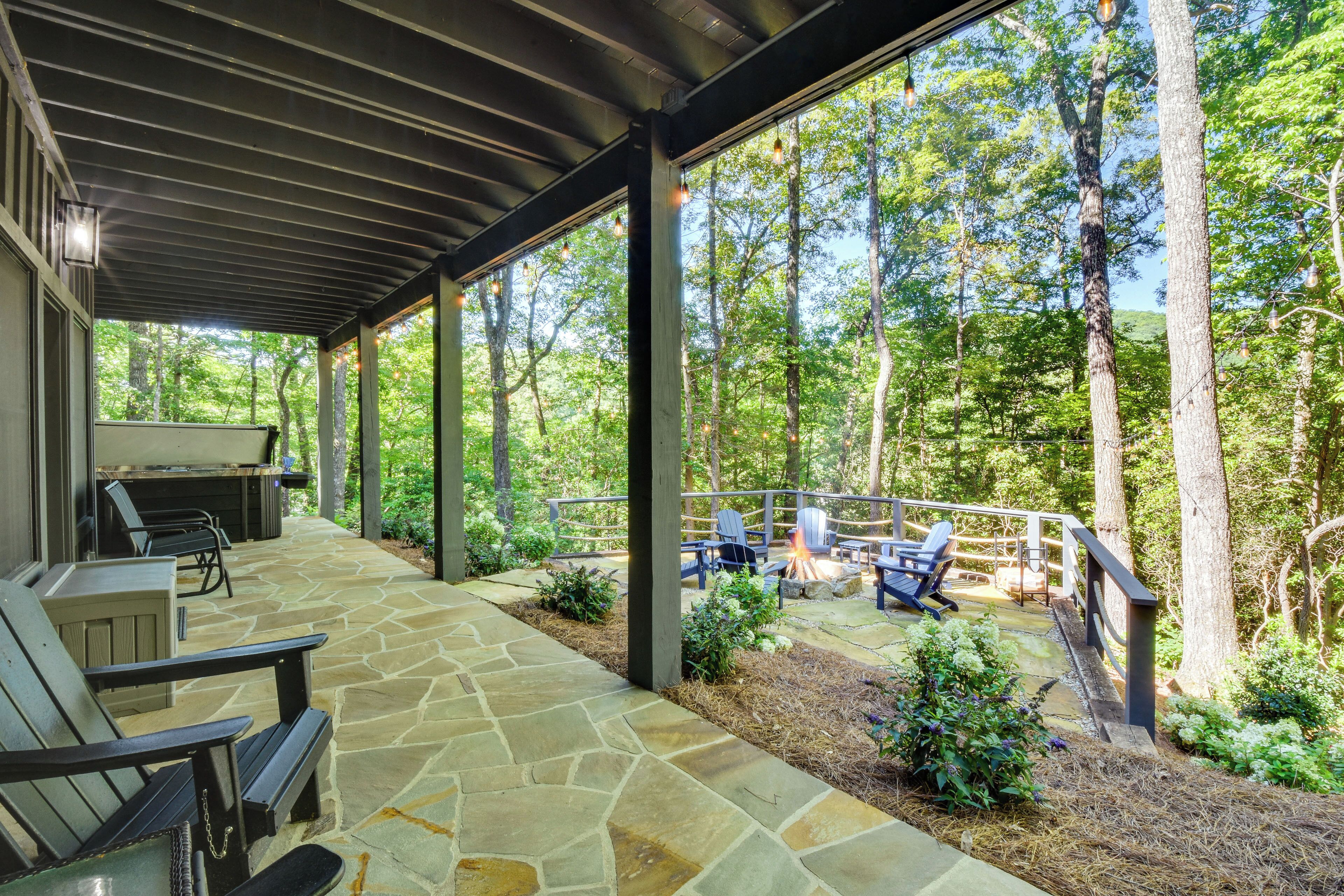 A covered patio with stone flooring, outdoor seating, and a fire pit.