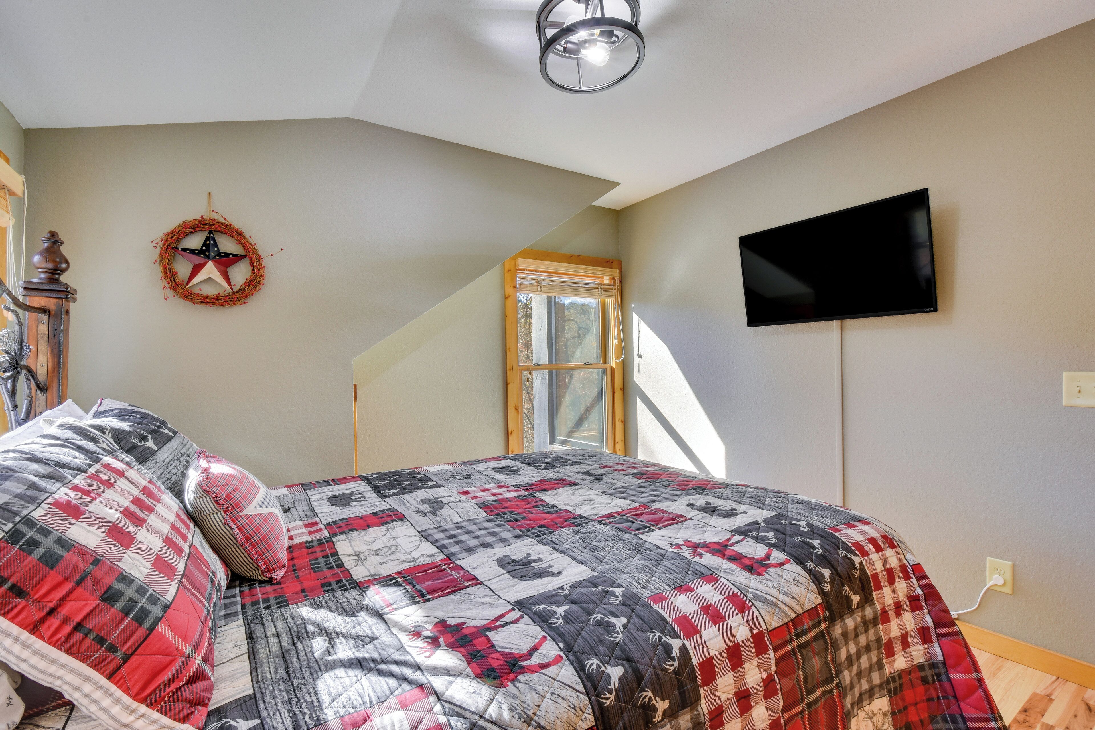 A bedroom with a large bed, a star decoration on the wall, a television, and a window with a wooden frame.