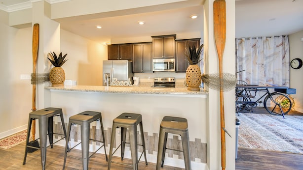A kitchen with a central island, bar stools, and a bicycle in the background. - Hampton Condo: By Convention Center & Coliseum! (Hampton)