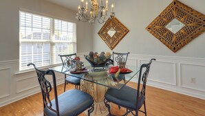 A dining area with a glass-top table, ornate chairs, a chandelier, and decorative wall mirrors. - Spacious Georgia Home w/ Deck, Grills & Fireplace! (Riverdale)