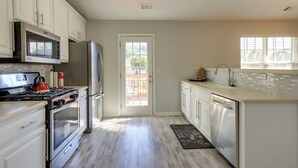 A modern kitchen with white cabinets, stainless steel appliances, and a tiled backsplash. - Spacious Georgia Home w/ Deck, Grills & Fireplace! (Riverdale)