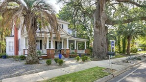 A two-story house with a porch, surrounded by trees and a well-maintained lawn. - Charming Thomasville Getaway: Walk to Downtown! (Thomasville)