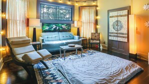 A room with a sofa, armchair, and a large bed with a patterned bedspread. - Charming Thomasville Getaway: Walk to Downtown! (Thomasville)
