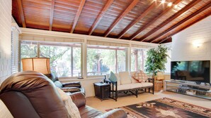 A living room with a wooden ceiling, a sofa, a TV, and a large window. - 5 Mi to Dtwn: Tuscon Escape w/ Yard & Patio! (Tucson)