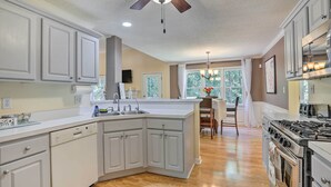 A modern kitchen with white cabinetry, a central island, and a stove. - Peaceful Dallas Home w/ Deck + Charcoal Grill (Dallas)