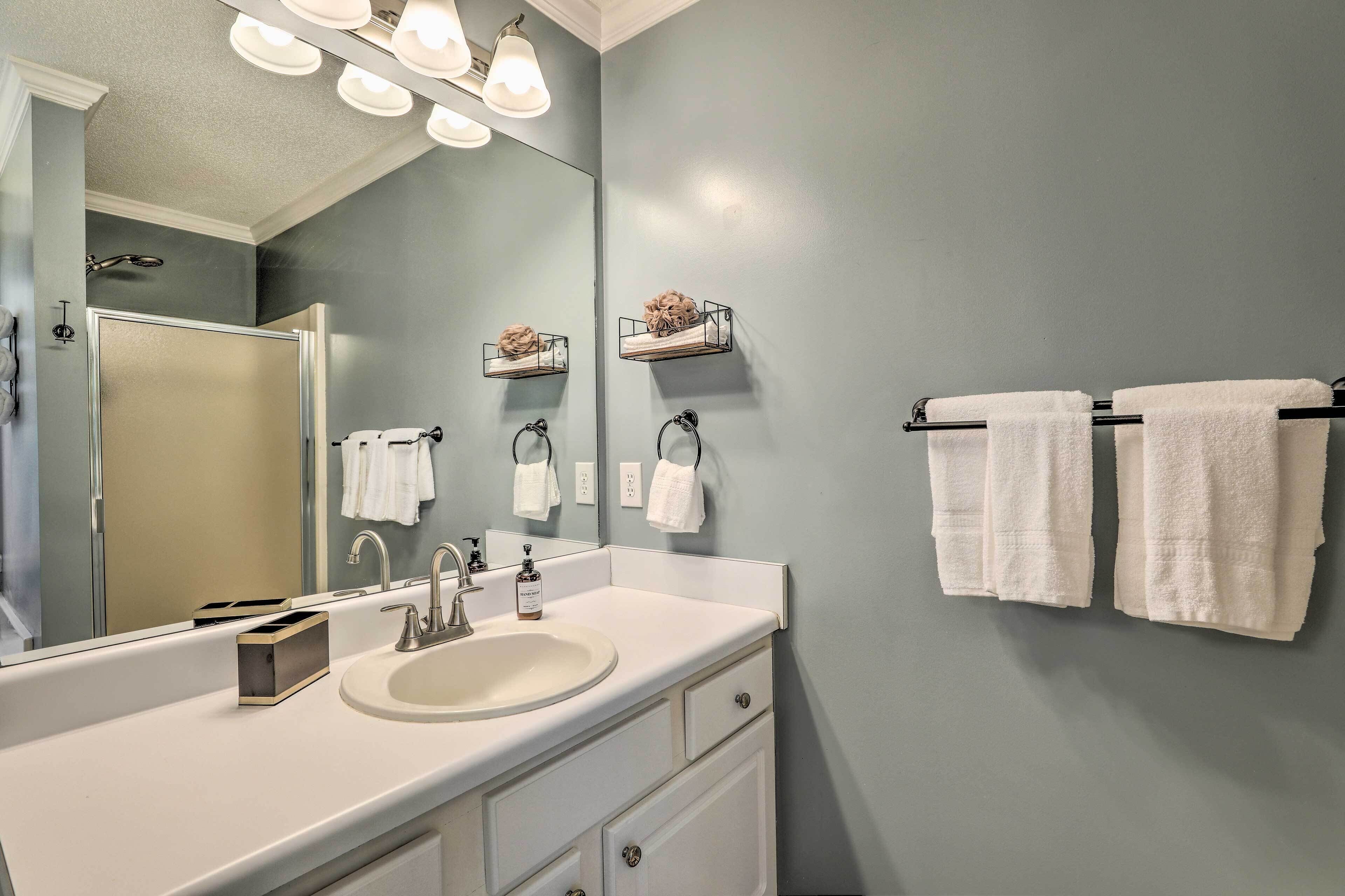 A bathroom with a large mirror, a sink, a towel rack, and a shower.