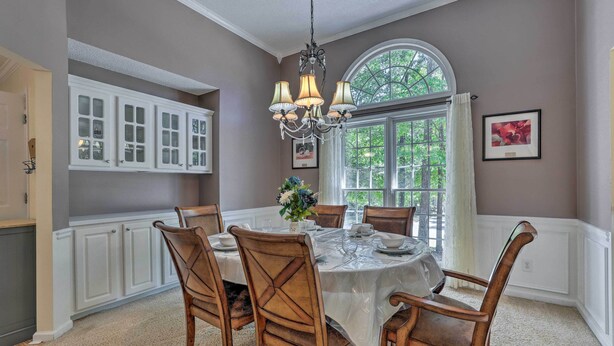 A dining room with a round table, chairs, a chandelier, and a window with a view of greenery. - Peaceful Dallas Home w/ Deck + Charcoal Grill (Dallas)