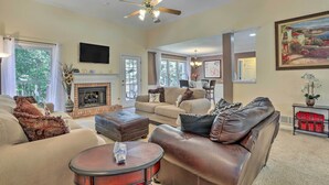 A spacious living room with a fireplace, leather sofas, a coffee table, and a ceiling fan. - Peaceful Dallas Home w/ Deck + Charcoal Grill (Dallas)