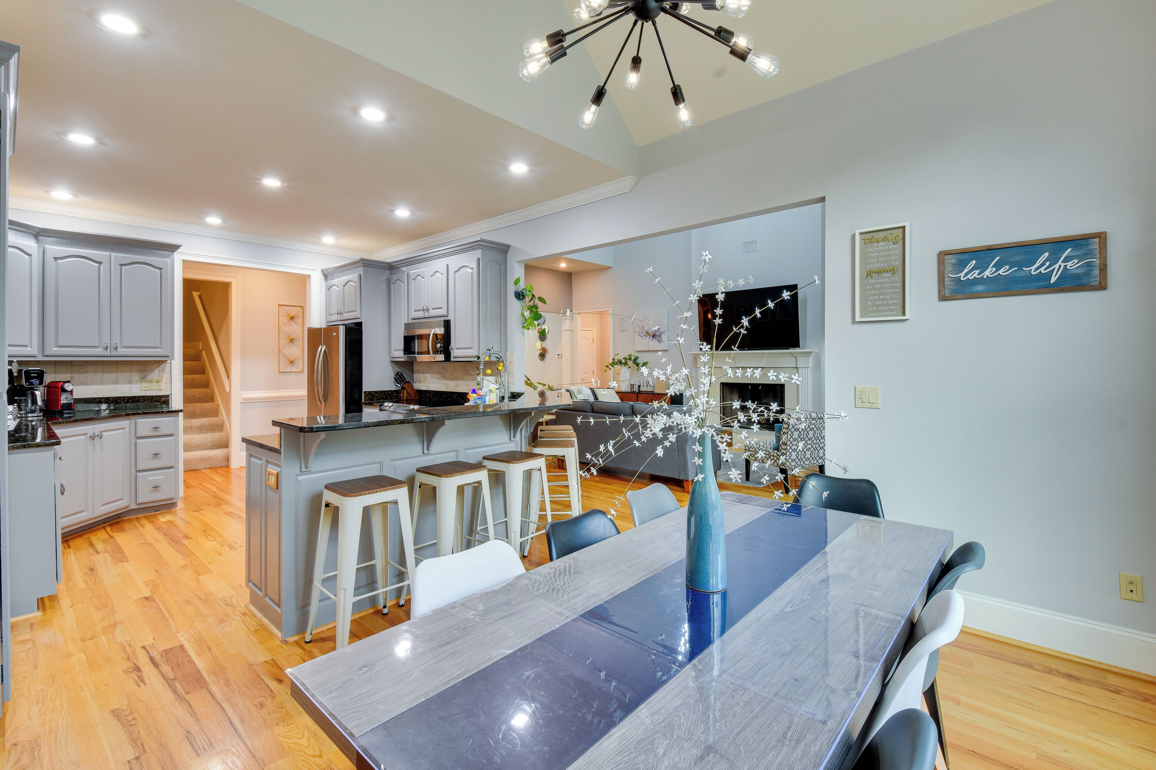 A modern kitchen with a central island, bar stools, and a dining table with chairs.