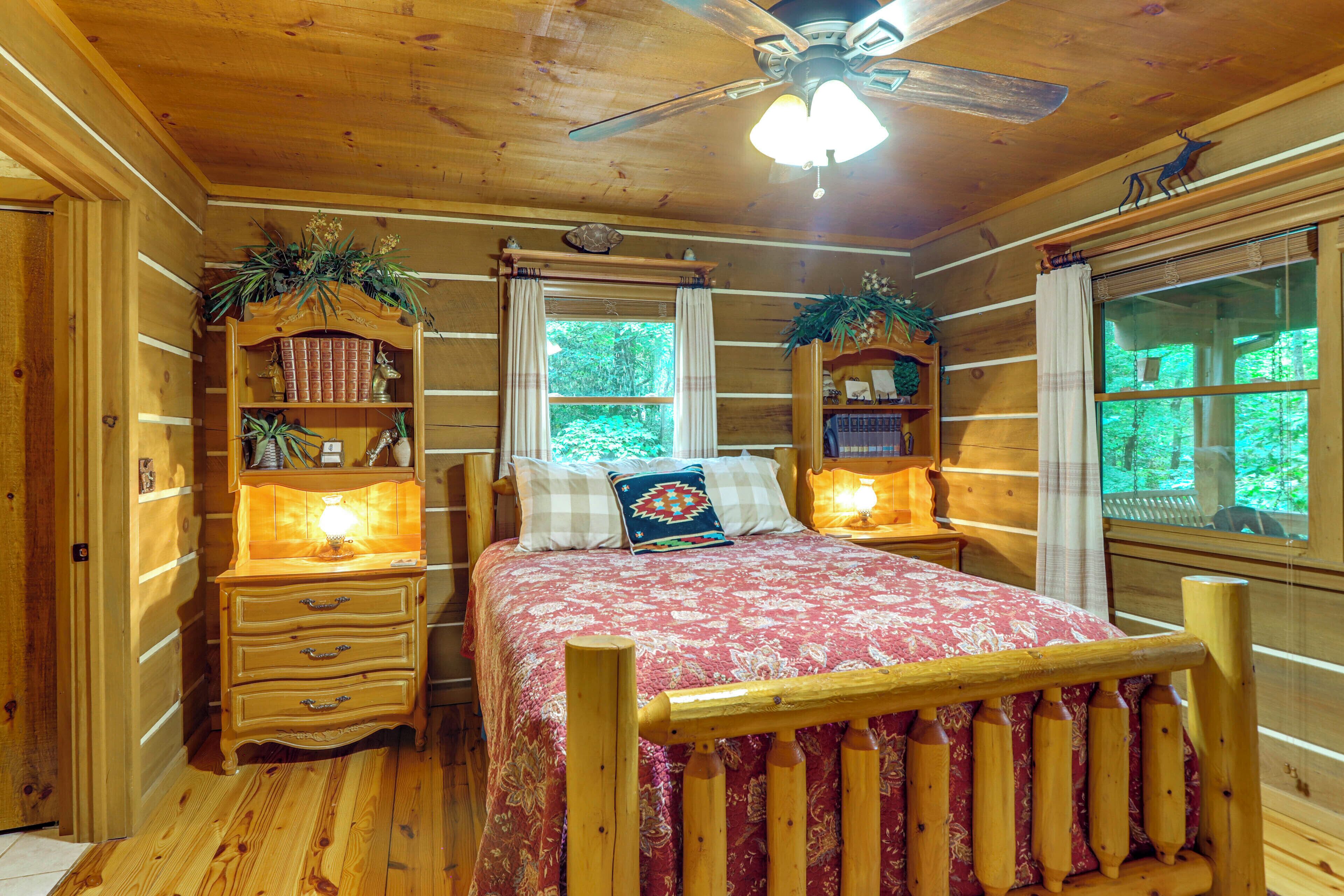 A wooden cabin bedroom with a bed, nightstands, a dresser, and a ceiling fan.