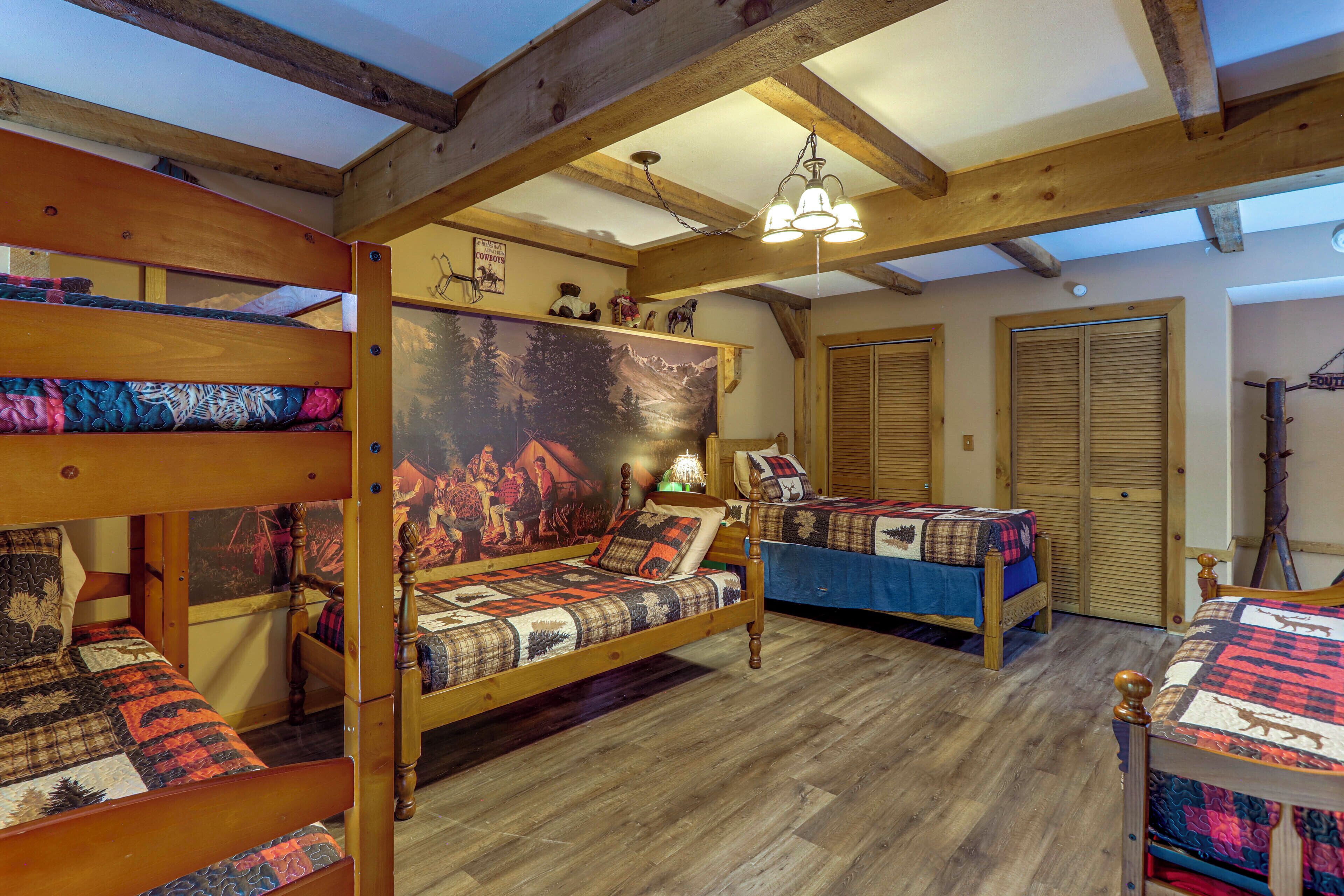A rustic room with wooden beds, a large painting, and a ceiling light.