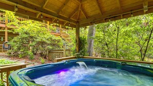 A hot tub under a wooden pergola with a view of a wooden deck and lush greenery. - 'drifting Feather' Mountain Cabin: Waterfront Deck (Blue Ridge)