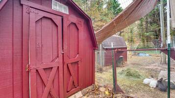 A red barn with a metal gate and a fenced area with hay and rocks.