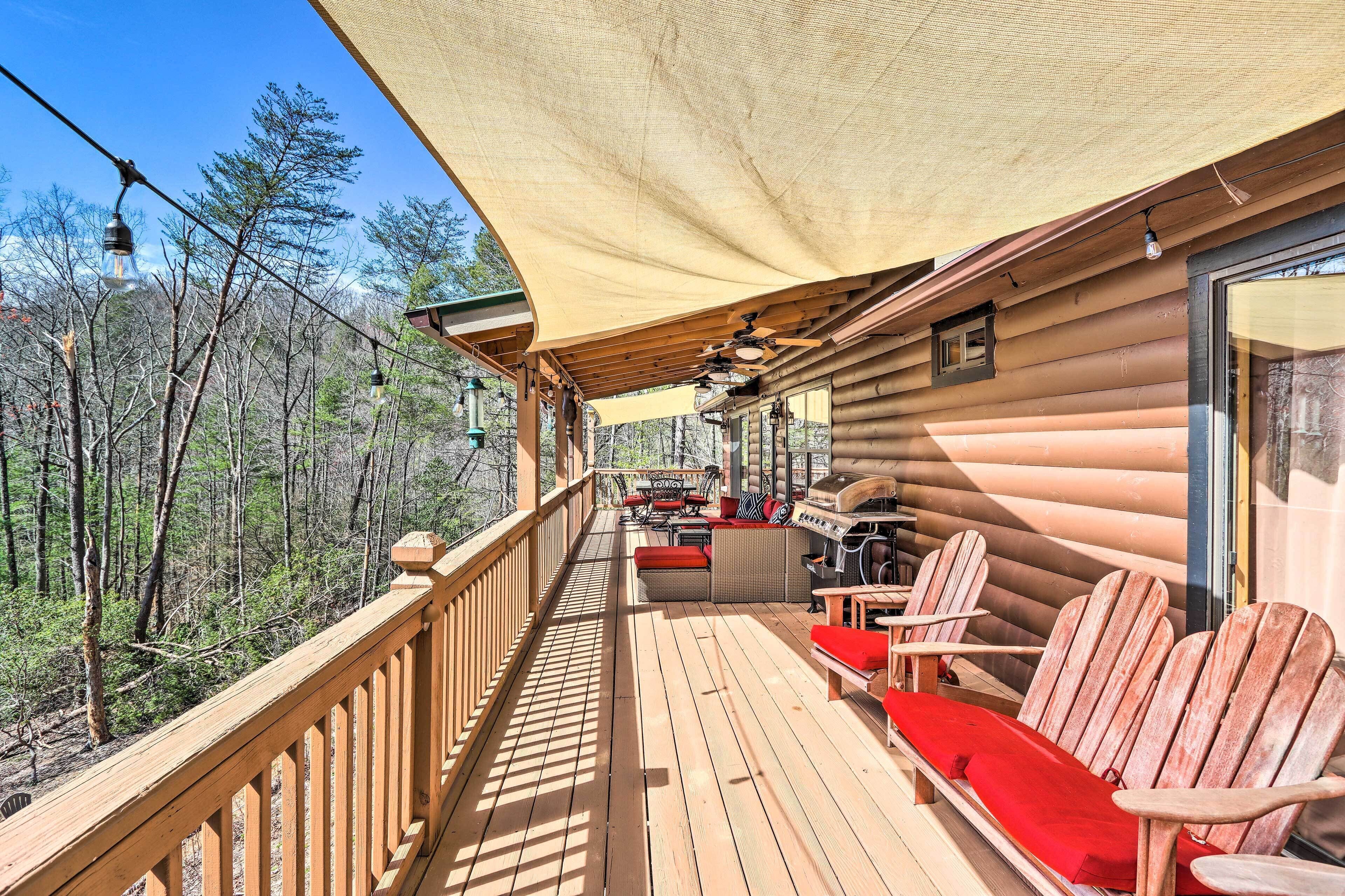 A wooden deck with outdoor seating, a barbecue area, and a view of the forest.