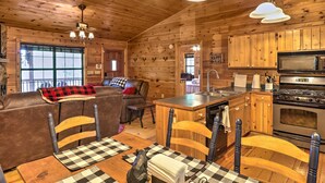 Un intérieur de chalet chaleureux comprenant un espace de vie, une table à manger et une cuisine.