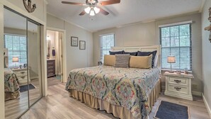 A bedroom with a bed, nightstands, a mirror, and a ceiling fan. - Lakeside Living: Sparta Retreat w/ Game Room! (Milledgeville)