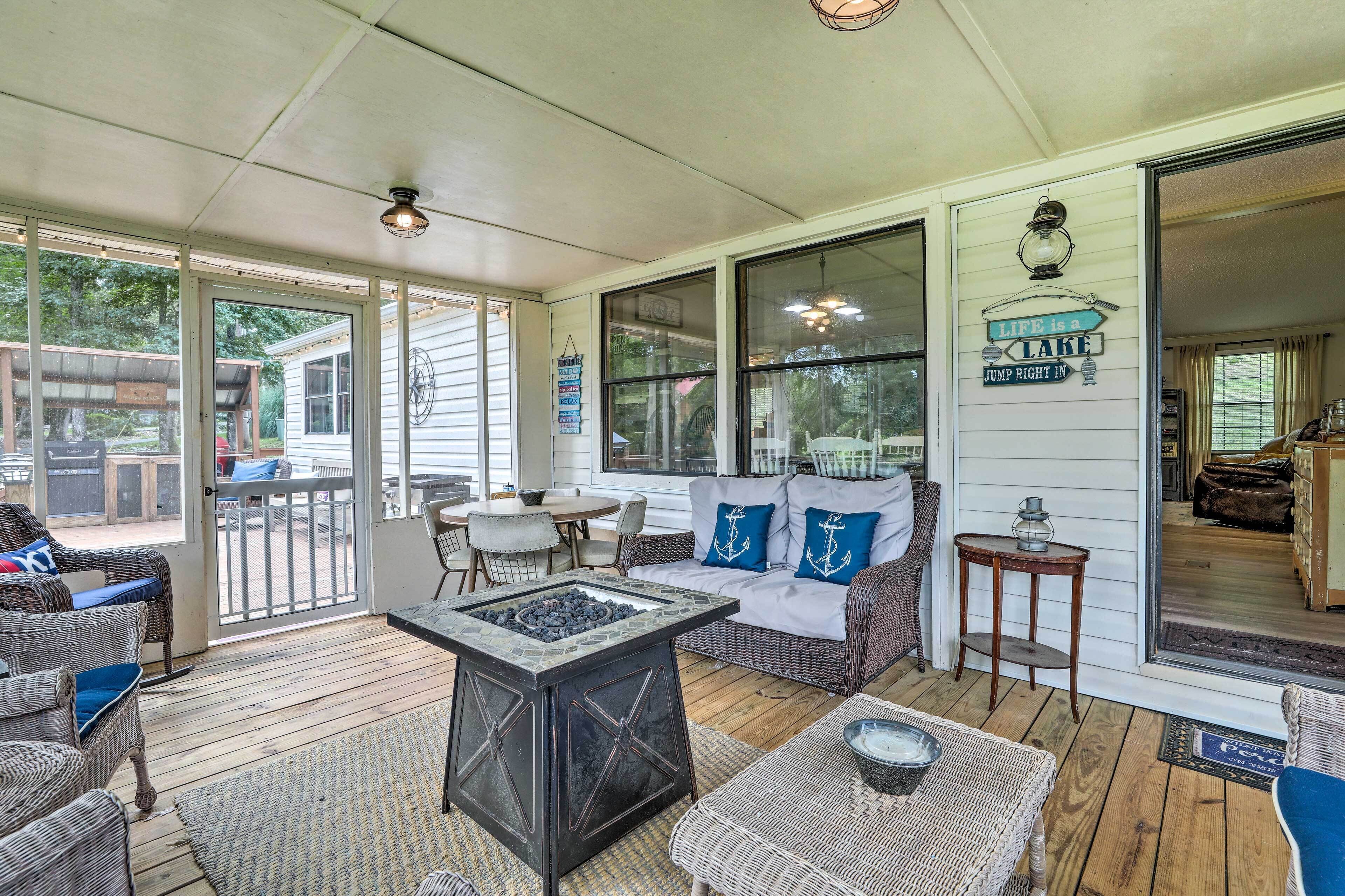A covered porch with wicker furniture, a fire pit, and a view of the backyard.