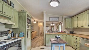 A kitchen with green cabinets, a wooden table, and a stove. - Lakeside Living: Sparta Retreat w/ Game Room! (Milledgeville)