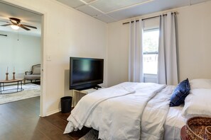 Un dormitorio con cama, televisor y ventana con cortinas.