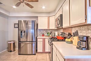 A modern kitchen with stainless steel appliances, white cabinetry, and a tiled backsplash. - Tucson House w/ Private Pool: 5 Mi to Downtown! (Tucson)
