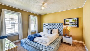 A bedroom with a tufted headboard, a bed with white linens, a bedside table with a lamp, and a window with curtains. - Georgia Vacation Rental: 3 Mi to Downtown Columbus (Columbus)