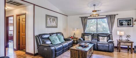 A spacious living room with a leather sofa, a coffee table, and a rustic wooden floor.