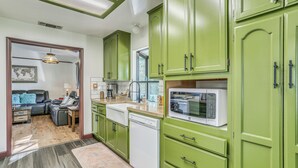 Une cuisine avec des meubles de couleur verte, un lave-vaisselle blanc et un four à micro-ondes.