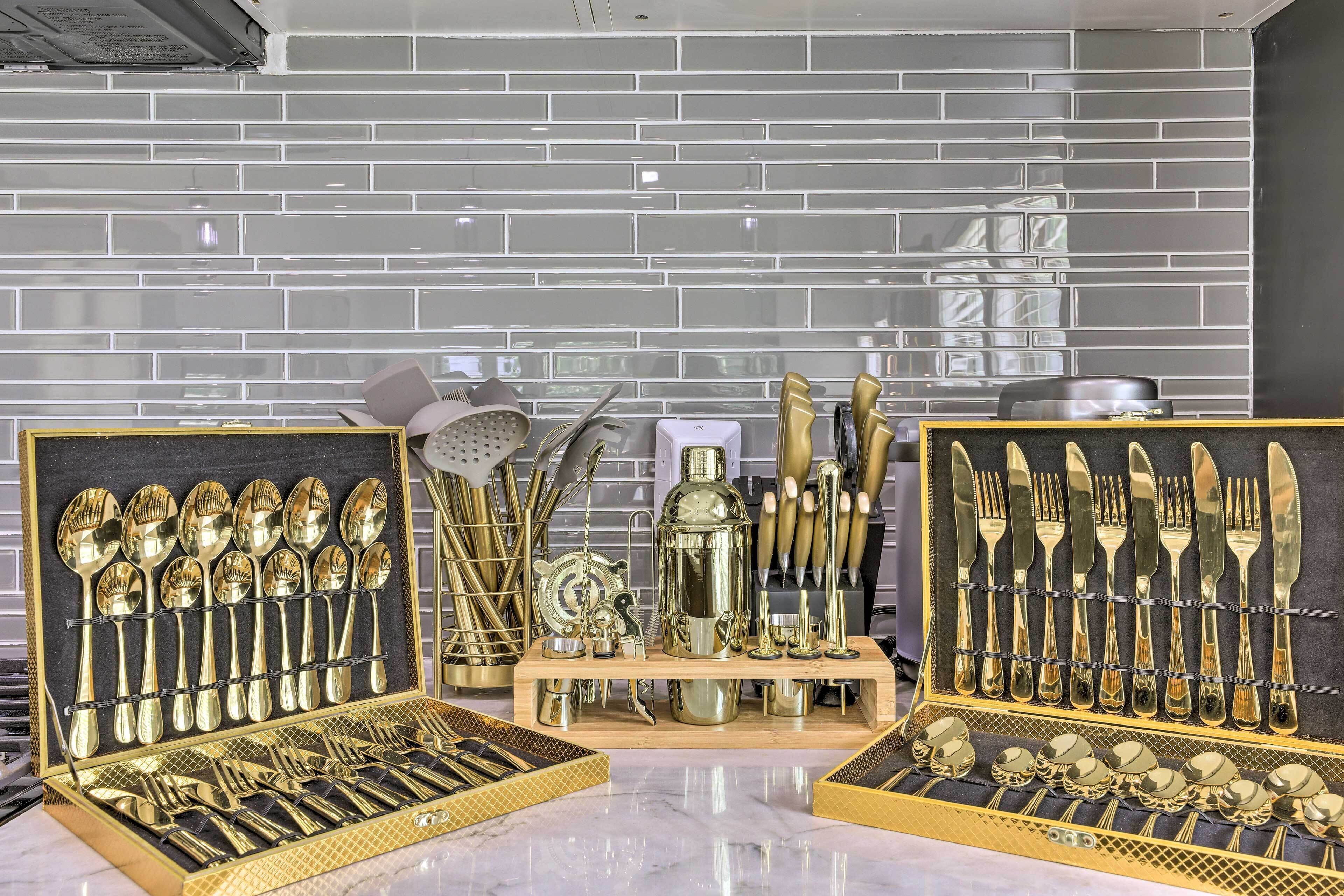 A display of gold-colored cutlery and kitchenware in a well-lit room with a tiled backsplash.