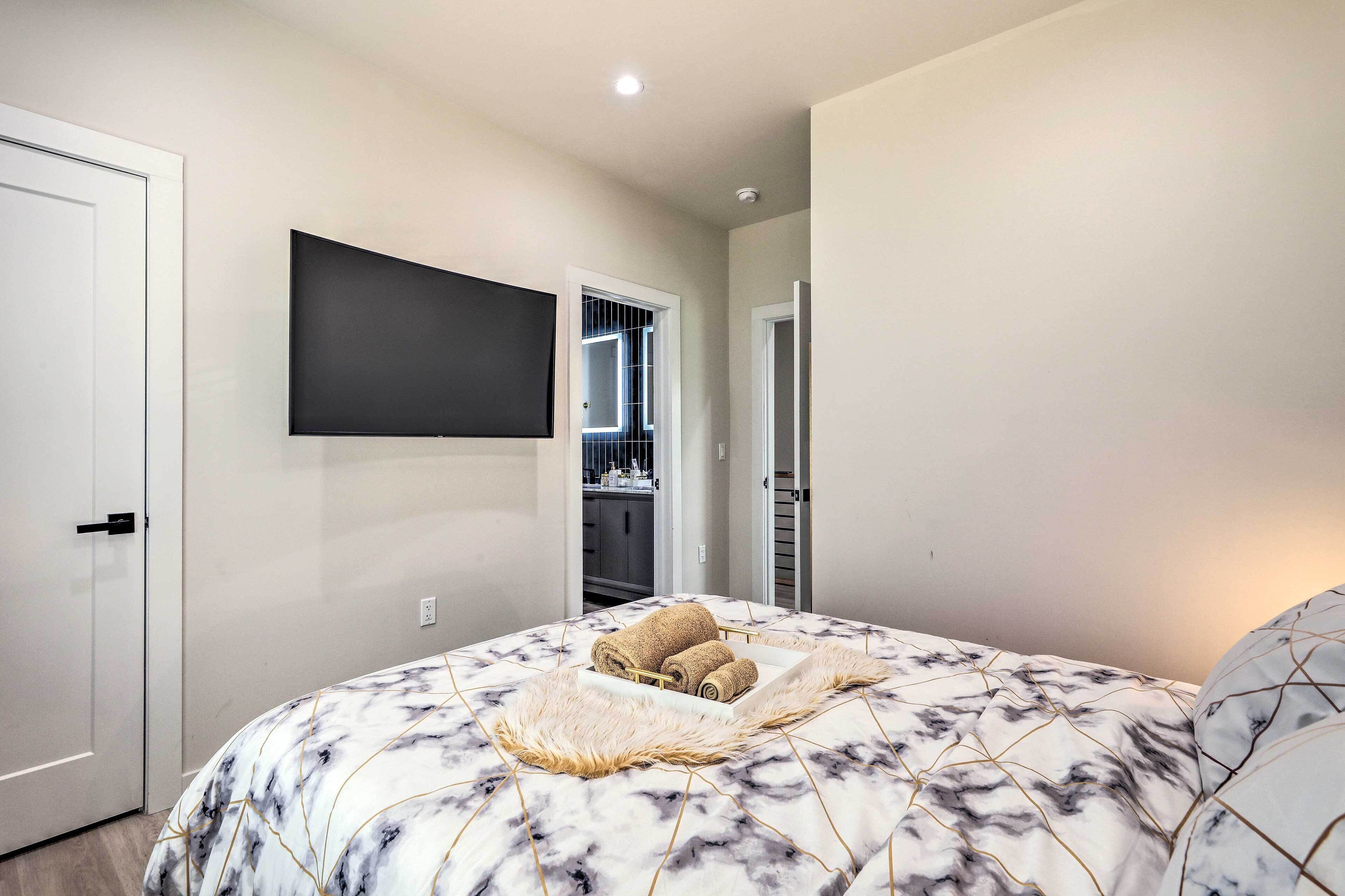 Une chambre à coucher comprenant un lit, un téléviseur à écran plat fixé au mur et un dressing.
