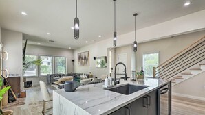A modern kitchen with a marble island, stainless steel appliances, and pendant lighting. - Luxury Smart Home: 2 Mi to Downtown Atlanta! (Atlanta)