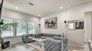 A modern living room with a sectional sofa, a coffee table, and a large abstract painting on the wall. - Luxury Smart Home: 2 Mi to Downtown Atlanta! (Atlanta)