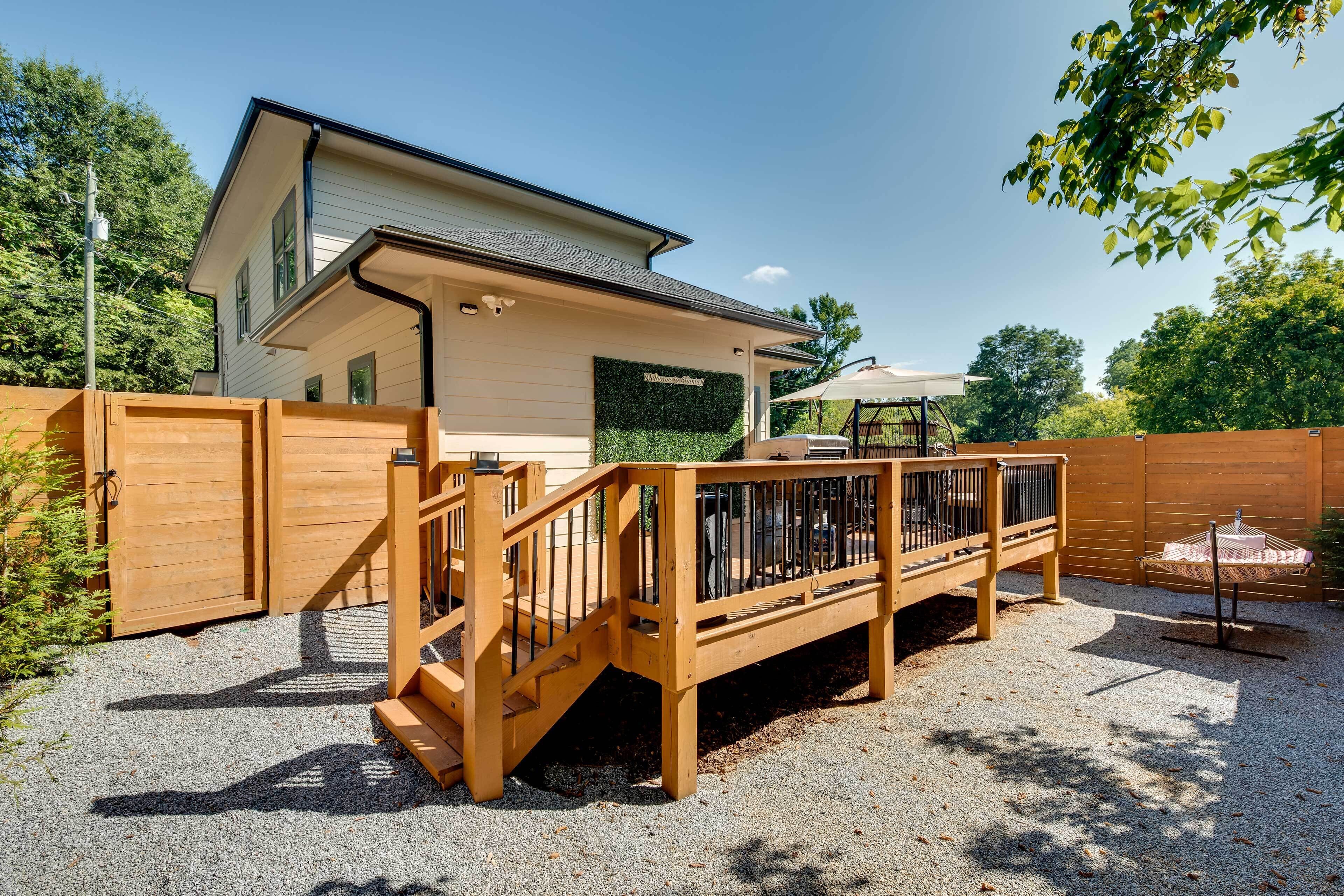 A house with a wooden deck, a covered patio, and a fenced yard.