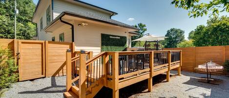 A house with a wooden deck, a covered patio, and a fenced yard.