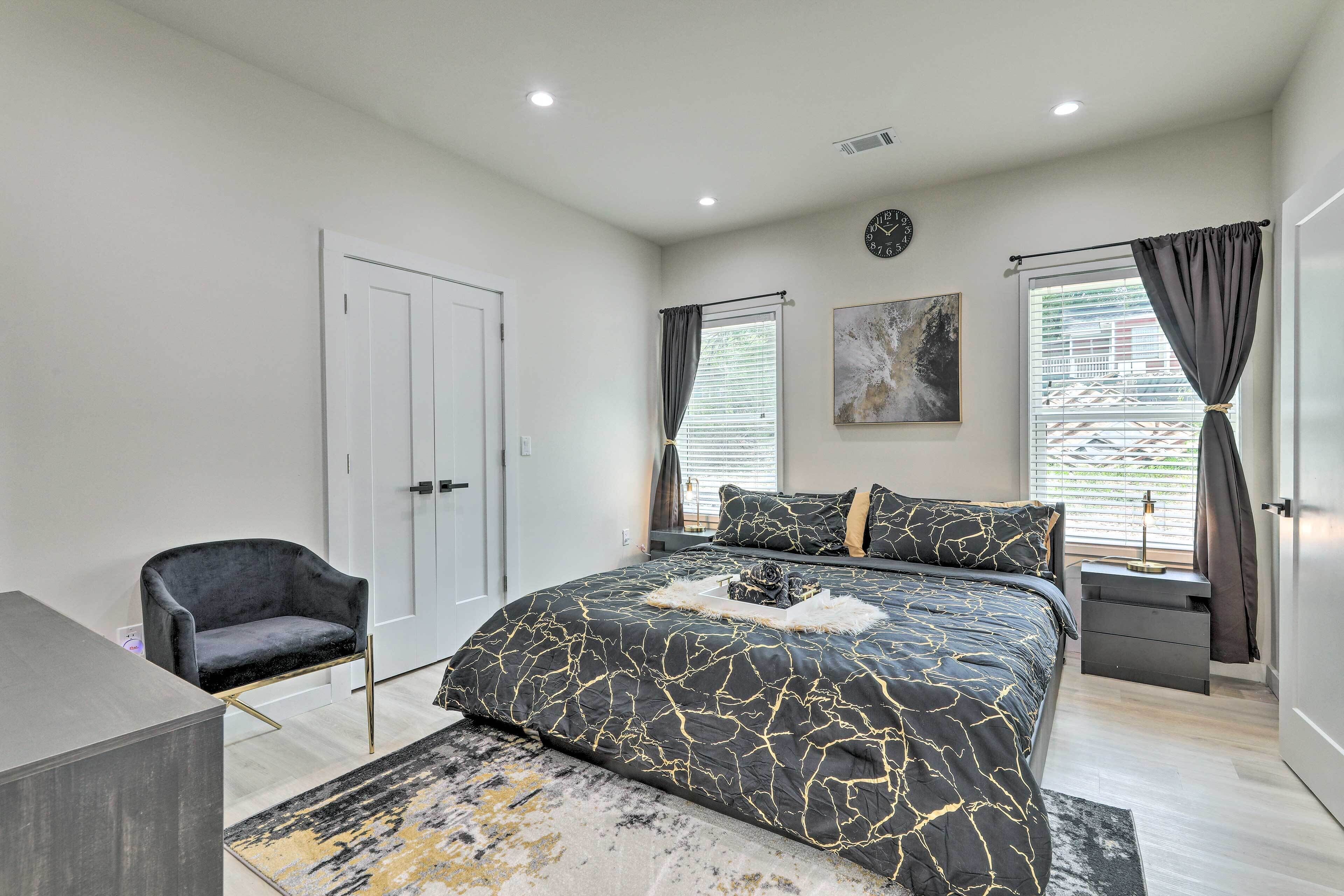 Une chambre moderne avec un grand lit, une chaise, un bureau et un tableau accroché au mur.