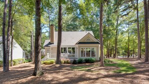 A house surrounded by tall trees with a porch and a chimney. - Stunning Lake Oconee Retreat w/ Pool Access! (Eatonton)