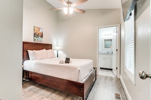 A bedroom with a wooden bed, a ceiling fan, a painting on the wall, and a bathroom visible through an open door. - 2 Mi to Village & Lake! Charming Helen Retreat (Helen)