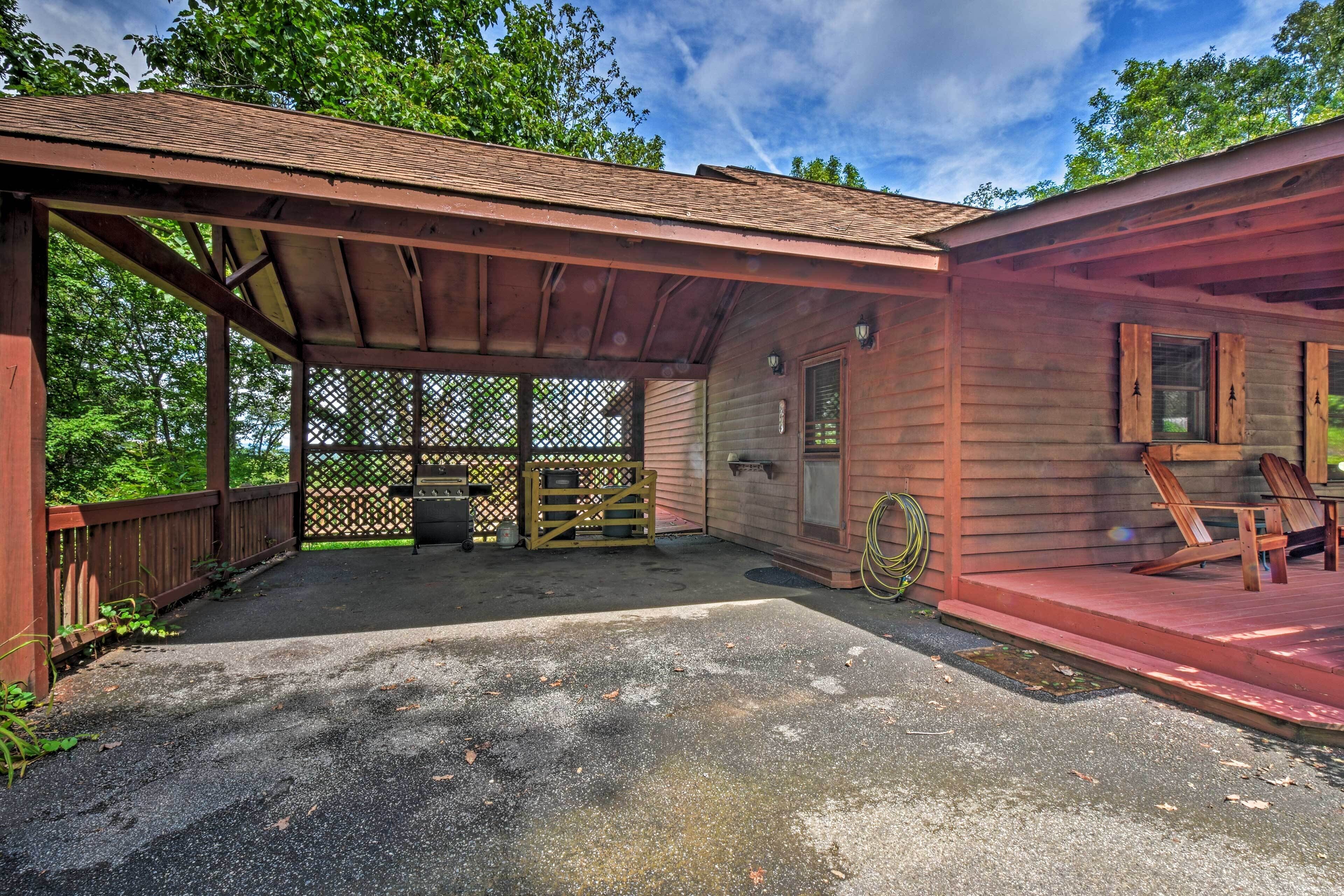 A wooden cabin with a covered porch, a fenced patio area, and a door with windows.