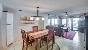 A spacious living area with a dining table, sofas, and a large window. - New Smyrna Beach Condo w/ Ocean-view Balcony! (New Smyrna Beach)
