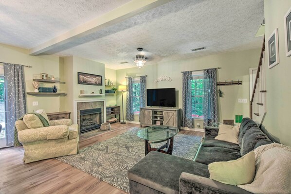 A living room with a fireplace, sofa, television, and a glass coffee table.